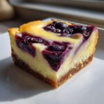 Close-up of a single serving of Gluten-Free Lemon Blueberry Cheesecake Squares with a graham cracker crust.