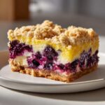 Close-up of a single serving of Gluten-Free Lemon Blueberry Layer Bars with a crumb topping.