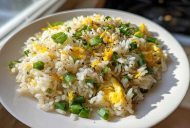 A close-up of a serving of Gluten-Free Lemon Pepper Fried Rice mixed with scrambled egg and topped with chopped green onions.