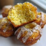 Close-up of Gluten-Free Lemon Poppy Seed Donut Holes, one cut open showing the moist interior dotted with poppy seeds and covered in lemon glaze.