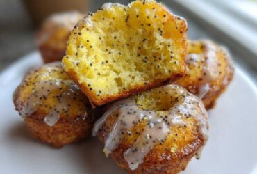 Close-up of Gluten-Free Lemon Poppy Seed Donut Holes, one cut open showing the moist interior dotted with poppy seeds and covered in lemon glaze.