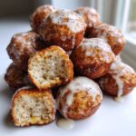 A stack of freshly baked Gluten-Free Lemon Poppy Seed Donut Holes drizzled with a thick lemon glaze.