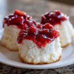 Three individual Gluten-Free Lemon Strawberry Angel Food Cups topped with glistening strawberry compote on a white plate.