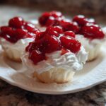 Close-up of several Gluten-Free Lemon Strawberry Angel Food Cups topped with whipped cream and glossy strawberries.