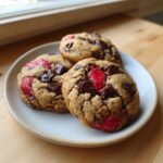 Three freshly baked Gluten-Free Strawberry Chocolate Chip Cookies piled on a small white plate.
