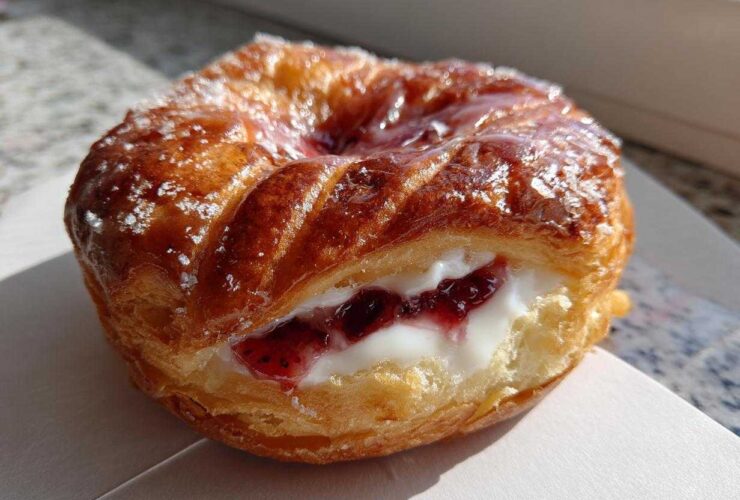 Close-up of a golden brown Gluten-Free Strawberry Cream Cheese Danish filled with white cream cheese and strawberry jam.