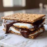 A decadent, double-layered HERSHEY'S S'mores sandwich featuring toasted marshmallows and dripping melted chocolate between graham crackers.