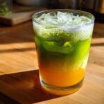 Close-up of a layered Iced Matcha Pineapple Refresher with bright green matcha foam over yellow pineapple juice and ice.