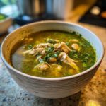 Close-up of a bowl filled with vibrant green Instant Pot Chicken Pozole Verde, featuring shredded chicken and white hominy.