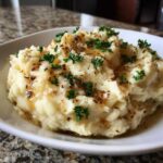 A close-up of fluffy Instant Pot Creamy Garlic Butter Potatoes topped with melted butter and fresh parsley.