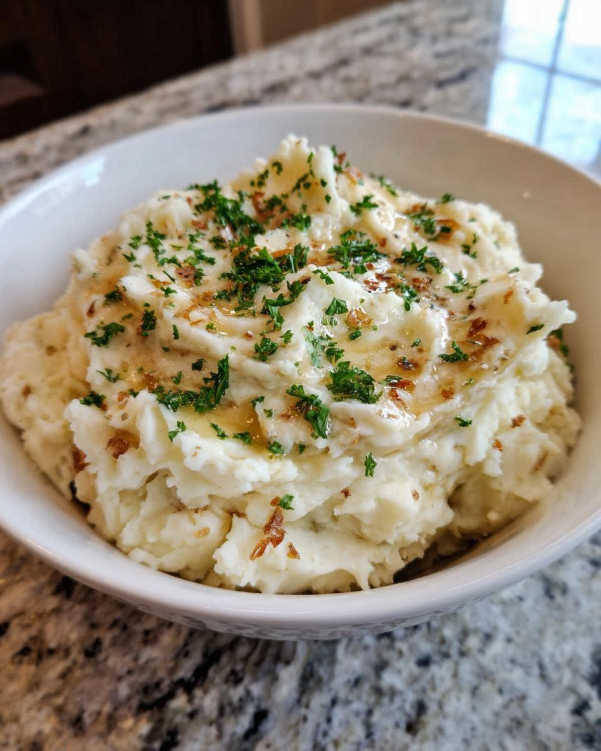 A close-up of creamy Instant Pot Creamy Garlic Butter Potatoes topped with melted butter and fresh parsley.