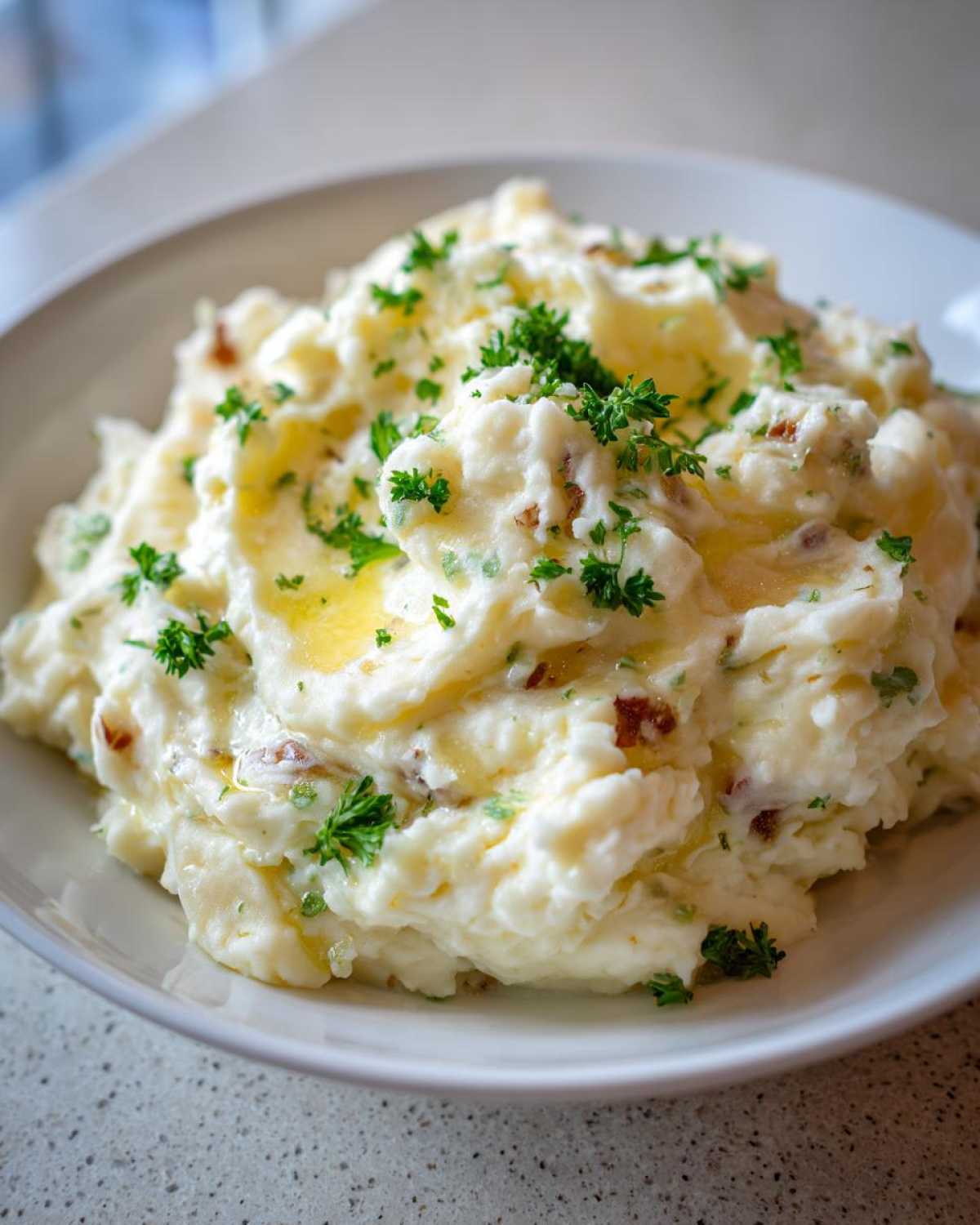 A close-up of fluffy Instant Pot Creamy Garlic Butter Potatoes topped with melted butter and fresh parsley.