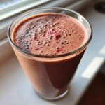 Close-up of a thick, rich Keto Chocolate Strawberry Smoothie topped with small red berry pieces.