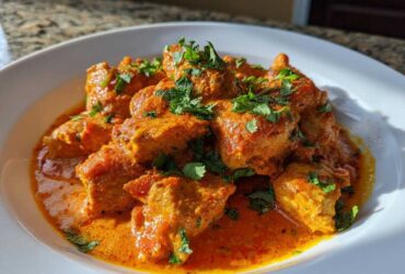 Close-up of rich, orange Keto Creamy Butter Chicken Skillet garnished with fresh cilantro.