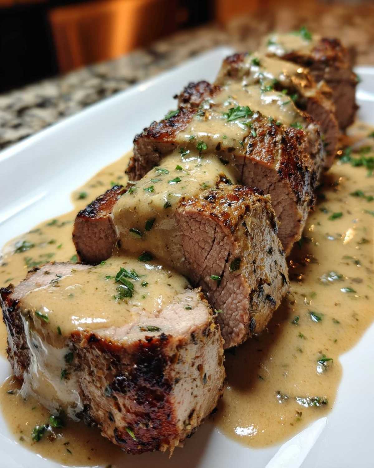 Slices of perfectly cooked Keto Creamy Garlic Herb Pork Tenderloin generously topped with a rich, herb-flecked sauce.