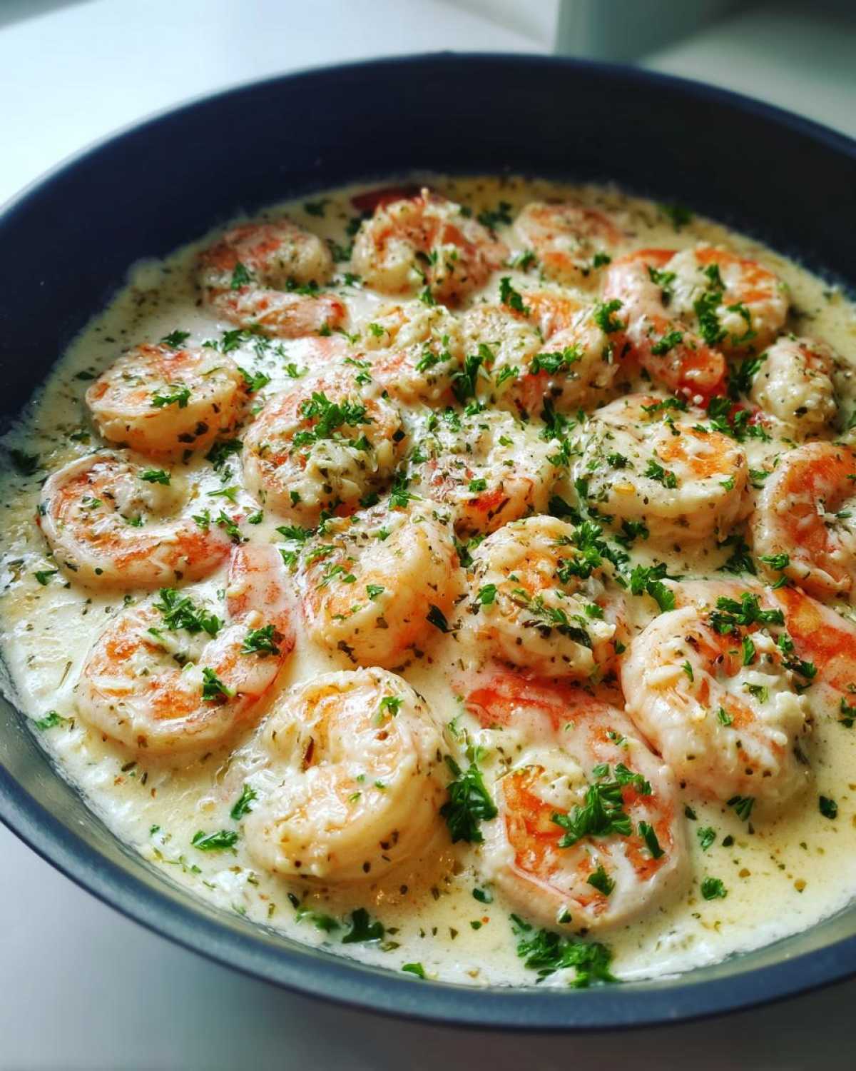 Close-up of cooked shrimp in a creamy garlic sauce, garnished with fresh parsley, from the Keto Creamy Garlic Shrimp Skillet.