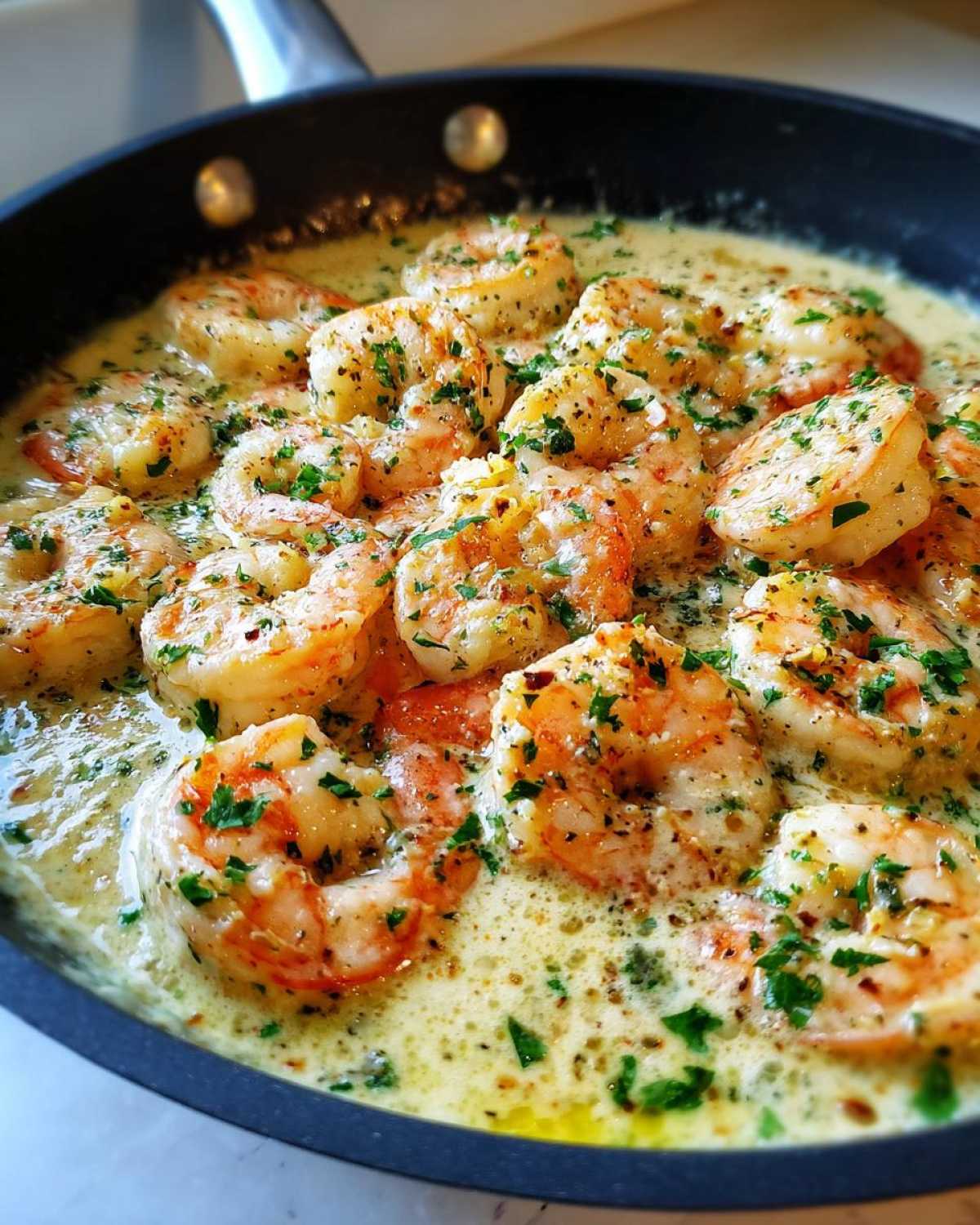 Close-up of plump shrimp simmering in a rich, creamy garlic sauce, garnished with fresh parsley in a black skillet, perfect for Keto Creamy Garlic Shrimp Skillet.