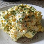 A scoop of rich Keto Creamy Herb Deviled Egg Salad topped with fresh chives and paprika on a white plate.