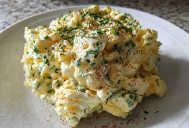 A scoop of rich Keto Creamy Herb Deviled Egg Salad topped with fresh chives and paprika on a white plate.