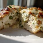 A cross-section view of Keto Creamy Jalapeno Popper Chicken, showing juicy white meat stuffed with melted cheese and green jalapeno pieces.