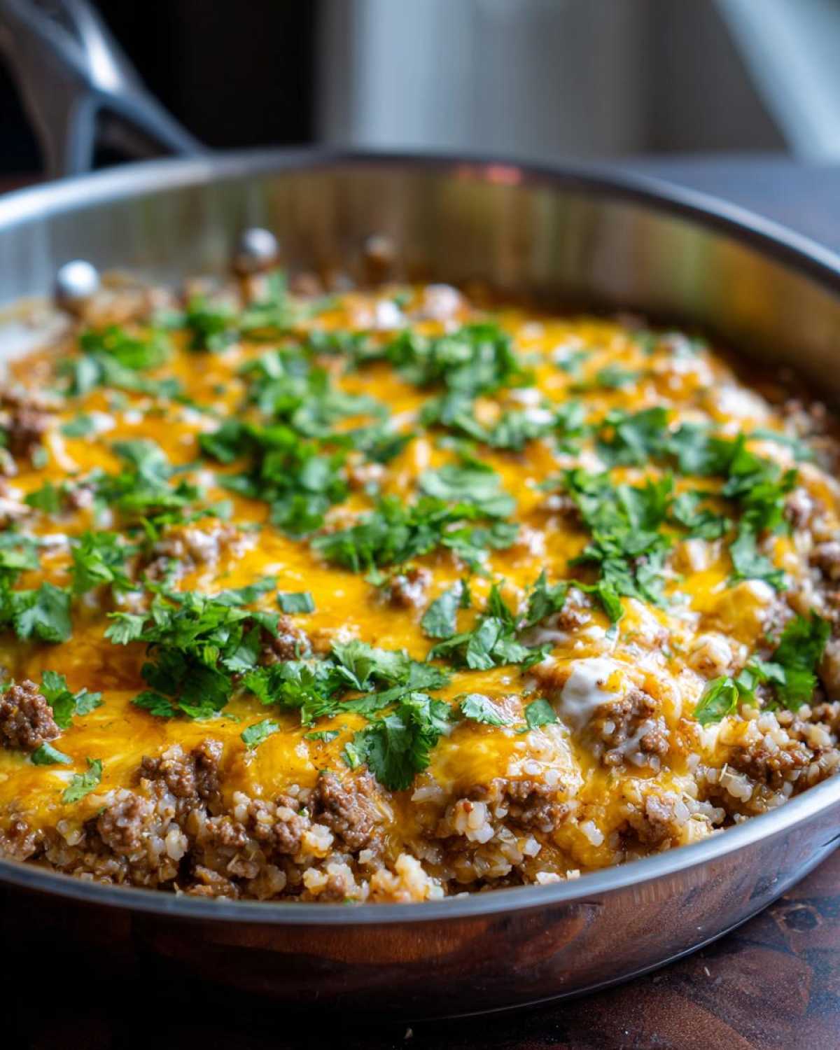 Close-up of Keto Creamy Taco Skillet with Cauliflower Rice topped with melted cheddar cheese and fresh cilantro.