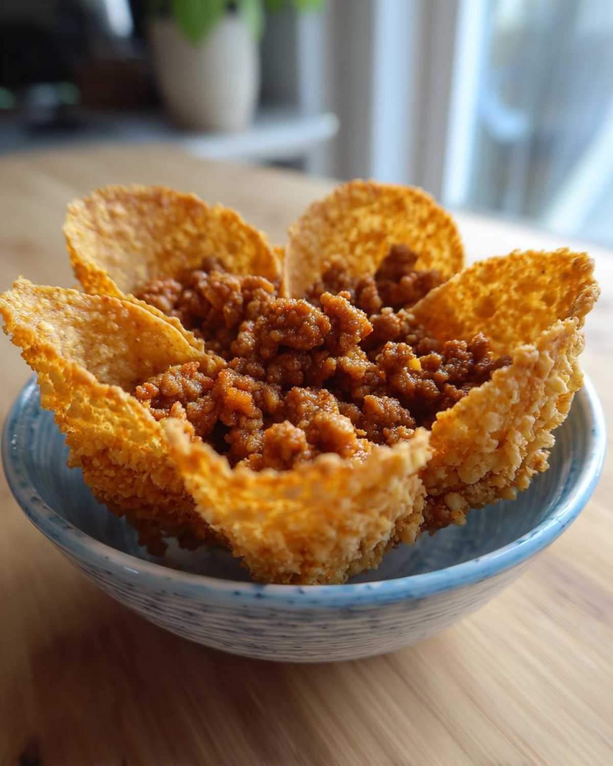 A close-up of one of the Keto Crispy Cheese Taco Shell Bowls filled with seasoned ground meat.