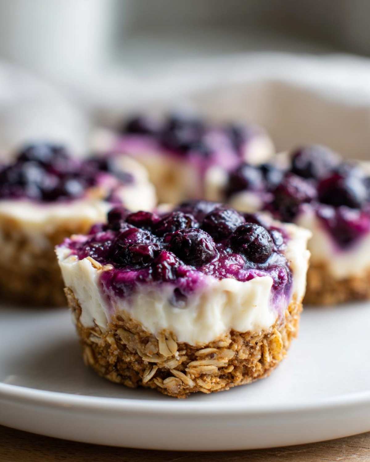 A close-up of one of the No-Bake Blueberry Cheesecake Oat Cups showing the oat crust, creamy filling, and blueberry topping.