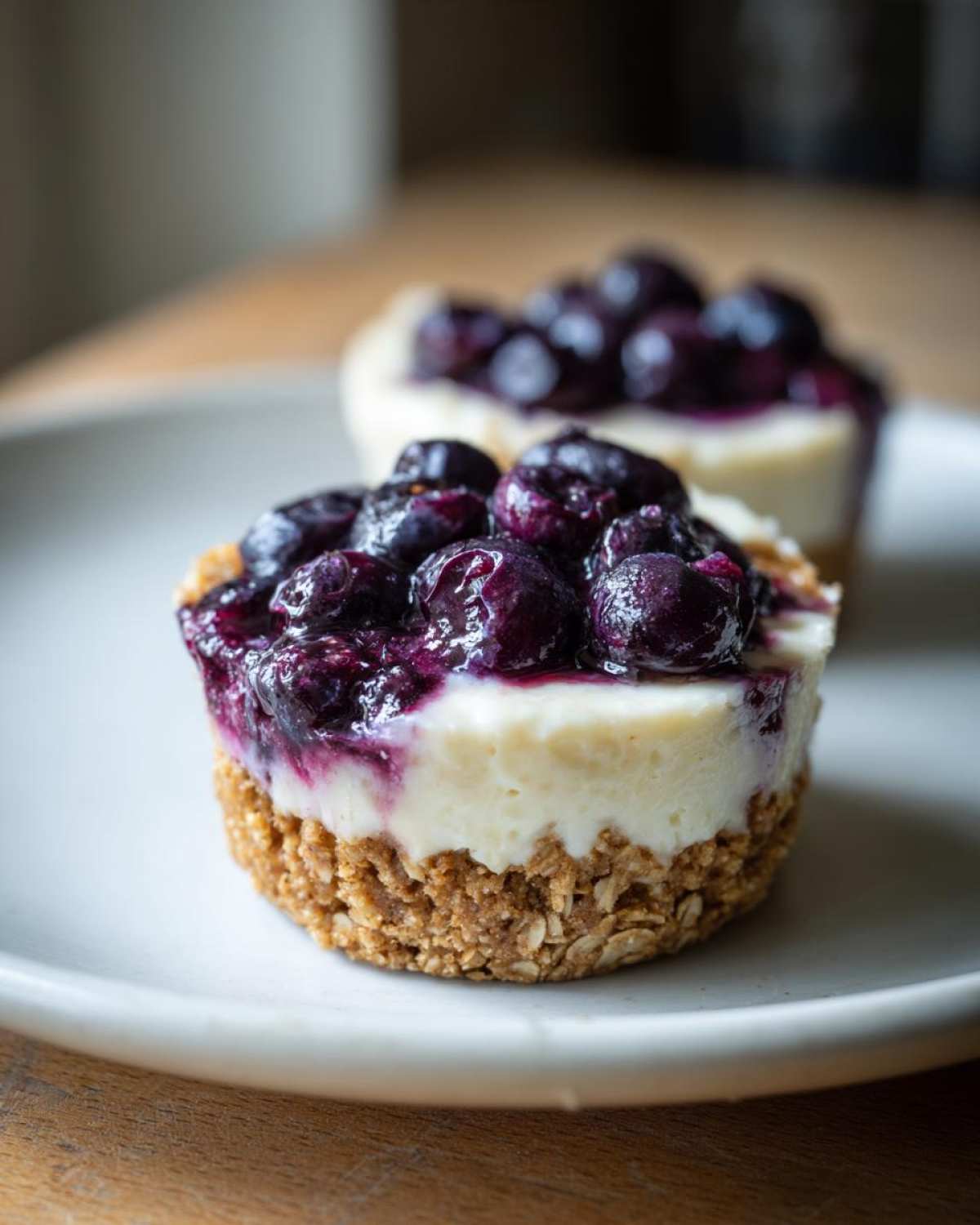 A close-up of a single No-Bake Blueberry Cheesecake Oat Cup with a thick oat crust, creamy filling, and blueberry topping.