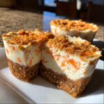 Close-up of a No-Bake Carrot Cake Cheesecake Cup cut in half, showing the graham cracker crust and creamy filling with visible carrot pieces.
