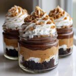 Three No-Bake Chocolate Peanut Butter Pie Jars layered with chocolate crust, peanut butter filling, and whipped cream topping.