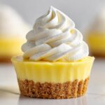 Close-up of a single No-Bake Lemon Cream Pie Cup featuring a graham cracker crust, bright yellow filling, and a swirl of whipped cream.