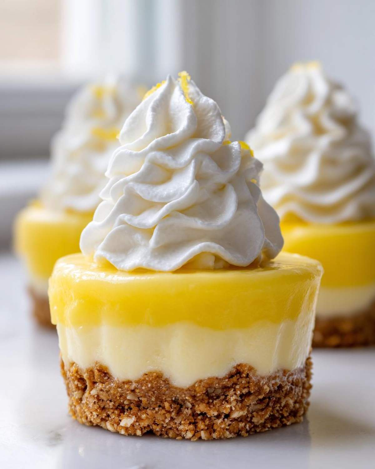 A single serving of No-Bake Lemon Cream Pie Cups topped with whipped cream and lemon zest.