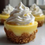 A close-up of one of the No-Bake Lemon Cream Pie Cups featuring a bright yellow filling, graham cracker crust, and a swirl of whipped cream.