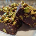Close-up of rich, dark No-Bake Pistachio Chocolate Fudge Squares topped with chopped pistachios.