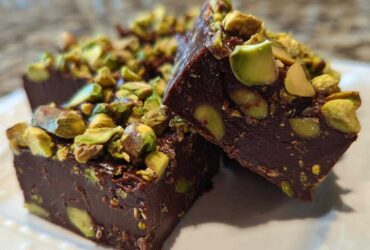 Close-up of rich, dark No-Bake Pistachio Chocolate Fudge Squares topped with chopped pistachios.