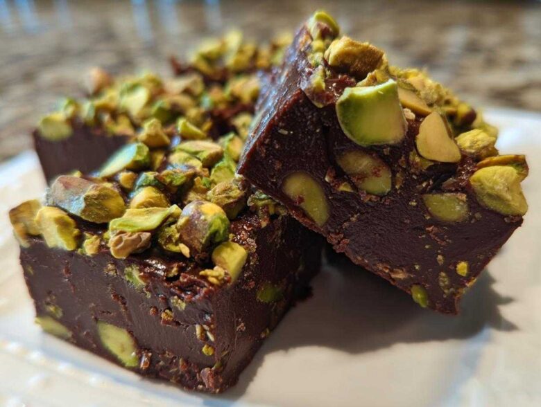 Close-up of rich, dark No-Bake Pistachio Chocolate Fudge Squares topped with chopped pistachios.