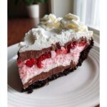 A tall slice of No-Bake Strawberry Chocolate Pudding Pie showing layers of chocolate, strawberry mousse, and whipped cream.