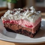 A rich slice of No-Bake Strawberry Chocolate Pudding Pie with layers of chocolate crust, mousse, strawberry filling, and whipped cream.