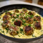 Close-up of browned One-Pan Creamy Lemon Garlic Turkey Meatballs simmering in a rich, yellow cream sauce and garnished with fresh parsley.