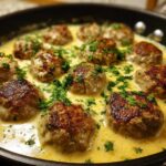 Close-up of browned turkey meatballs simmering in a creamy lemon garlic sauce, garnished with fresh parsley.