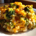 A close-up serving of One-Pot Creamy Broccoli Cheddar Rice, featuring bright green broccoli florets and melted cheddar cheese over rice.