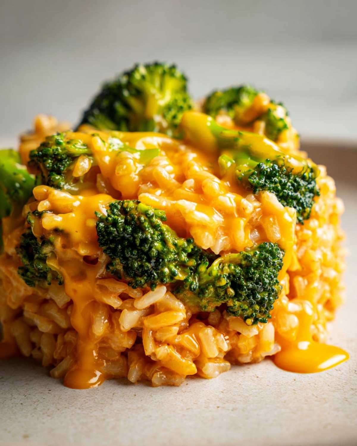 Close-up of a serving of One-Pot Creamy Broccoli Cheddar Rice topped with bright green broccoli florets and rich cheese sauce.