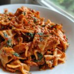 Close-up of One-Pot Creamy Tomato Basil Tortilla Pasta featuring farfalle pasta coated in a rich, creamy tomato sauce with visible basil.
