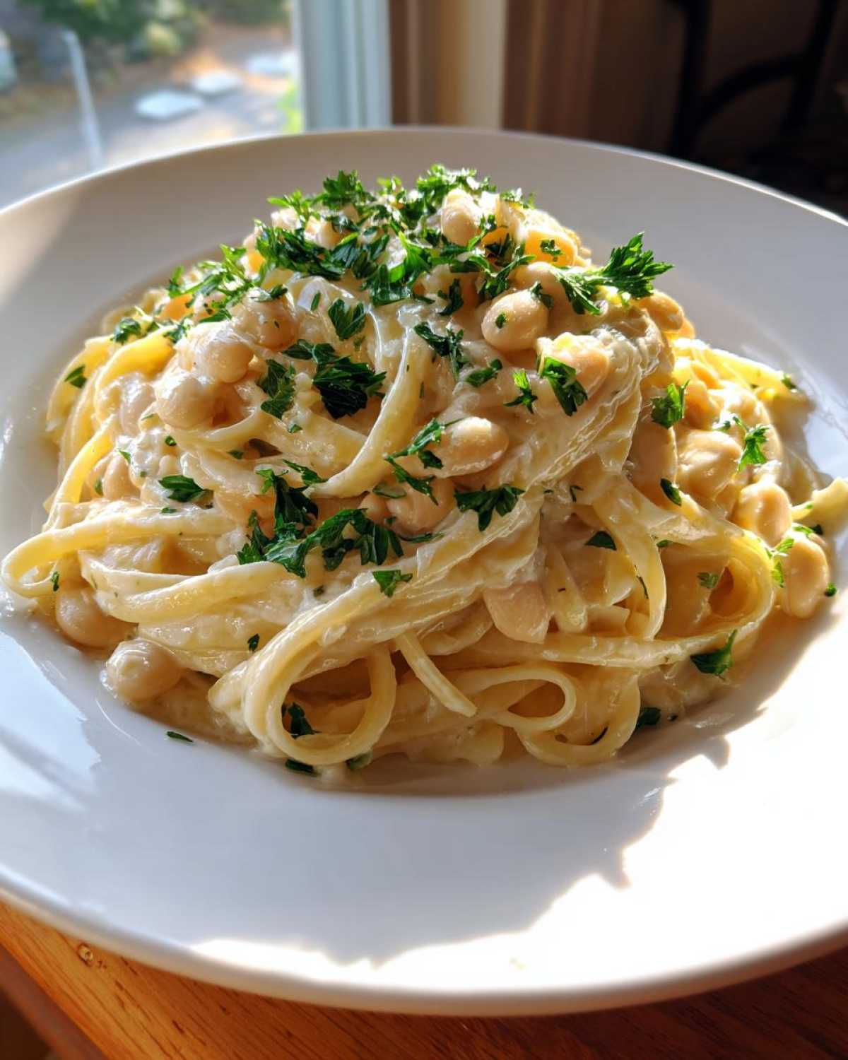 A close-up of a serving of One-Pot Creamy White Bean Lemon Pasta topped with fresh parsley.