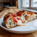 A thick slice of homemade pizza showing a beautiful airy crust, melted mozzarella cheese pull, and bright tomato sauce, illustrating Secrets to Perfect Pizza at Home.