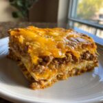 A close-up, appetizing slice of Pioneer Woman Taco Casserole layered with seasoned ground beef and melted cheddar cheese.