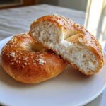 A sesame seed Cottage Cheese Bagels Breakfast sliced in half, showing the soft, white interior texture.