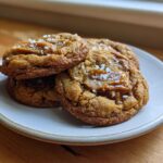 A stack of three Soft Batch Salted Caramel Cookies topped with gooey caramel and flaky sea salt.