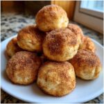 A close-up stack of freshly baked Soft & Sweet Cinnamon Sugar Biscuit Bites coated in cinnamon sugar.