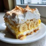 A tall, layered slice of spectacular Banana Pudding featuring vanilla wafers, sliced bananas, custard, and toasted meringue.